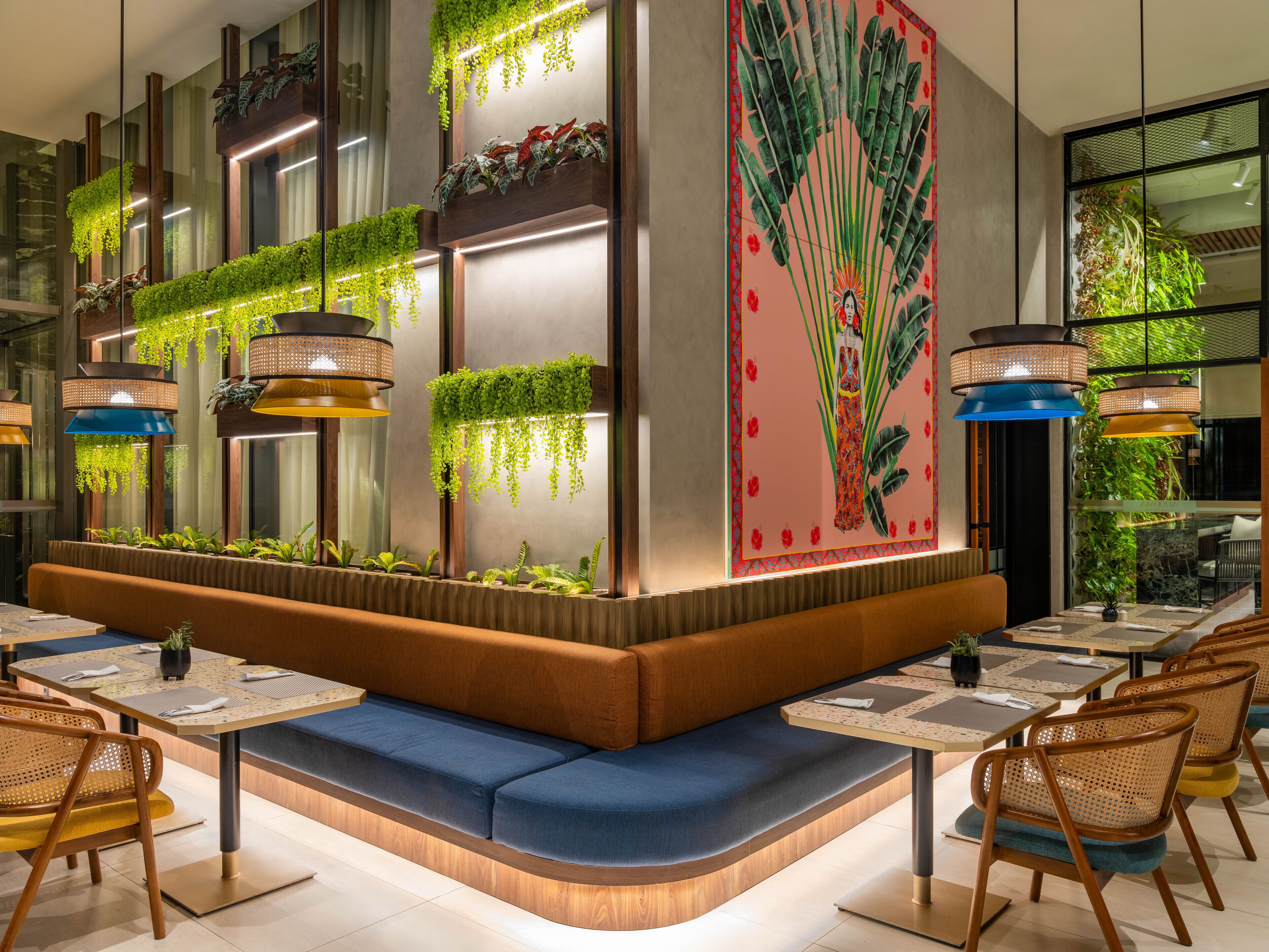 A modern interior with a seating area, tables, hanging plants, and a decorative wall.