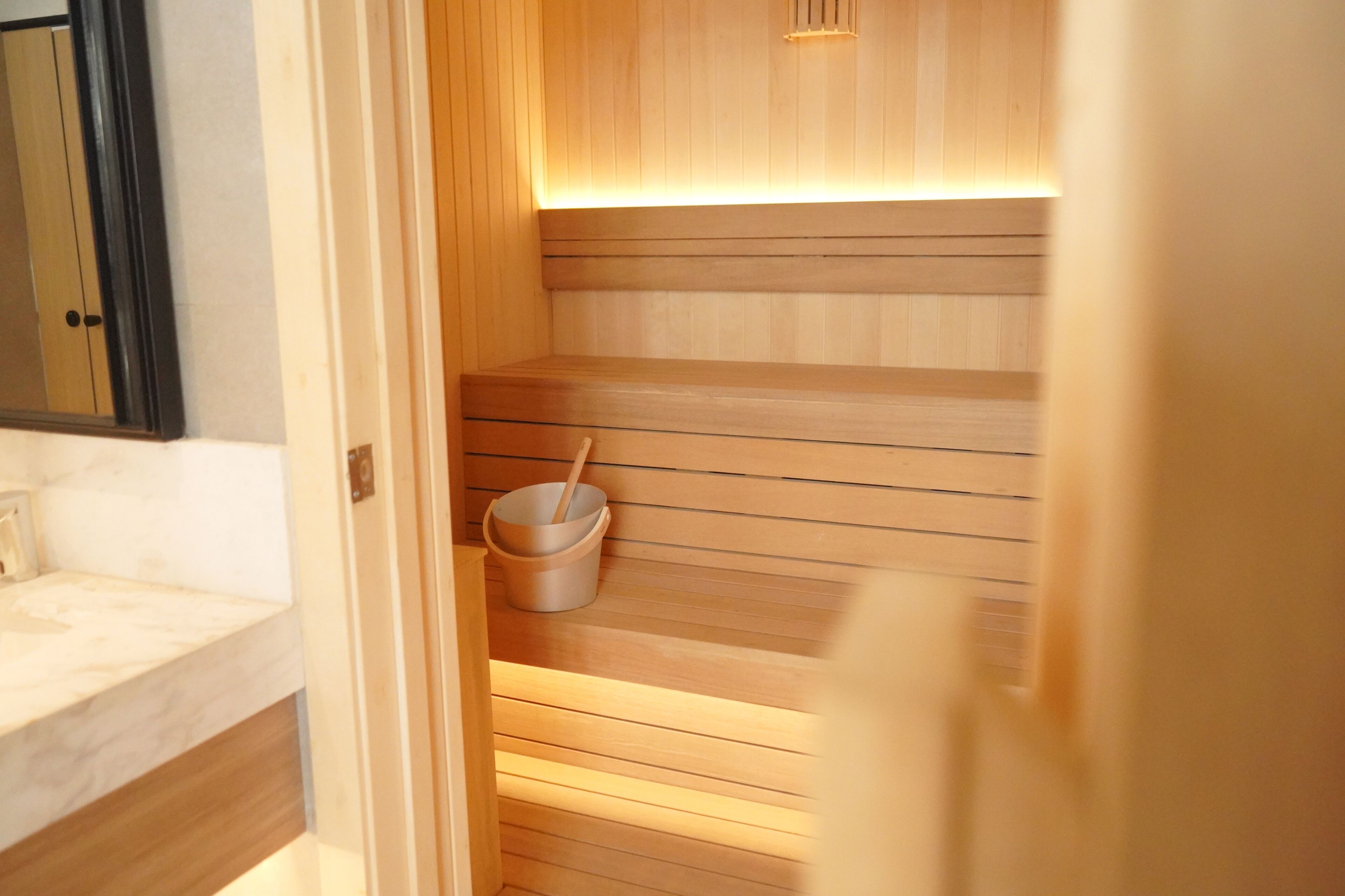 A sauna with wooden benches and a bucket with a brush.