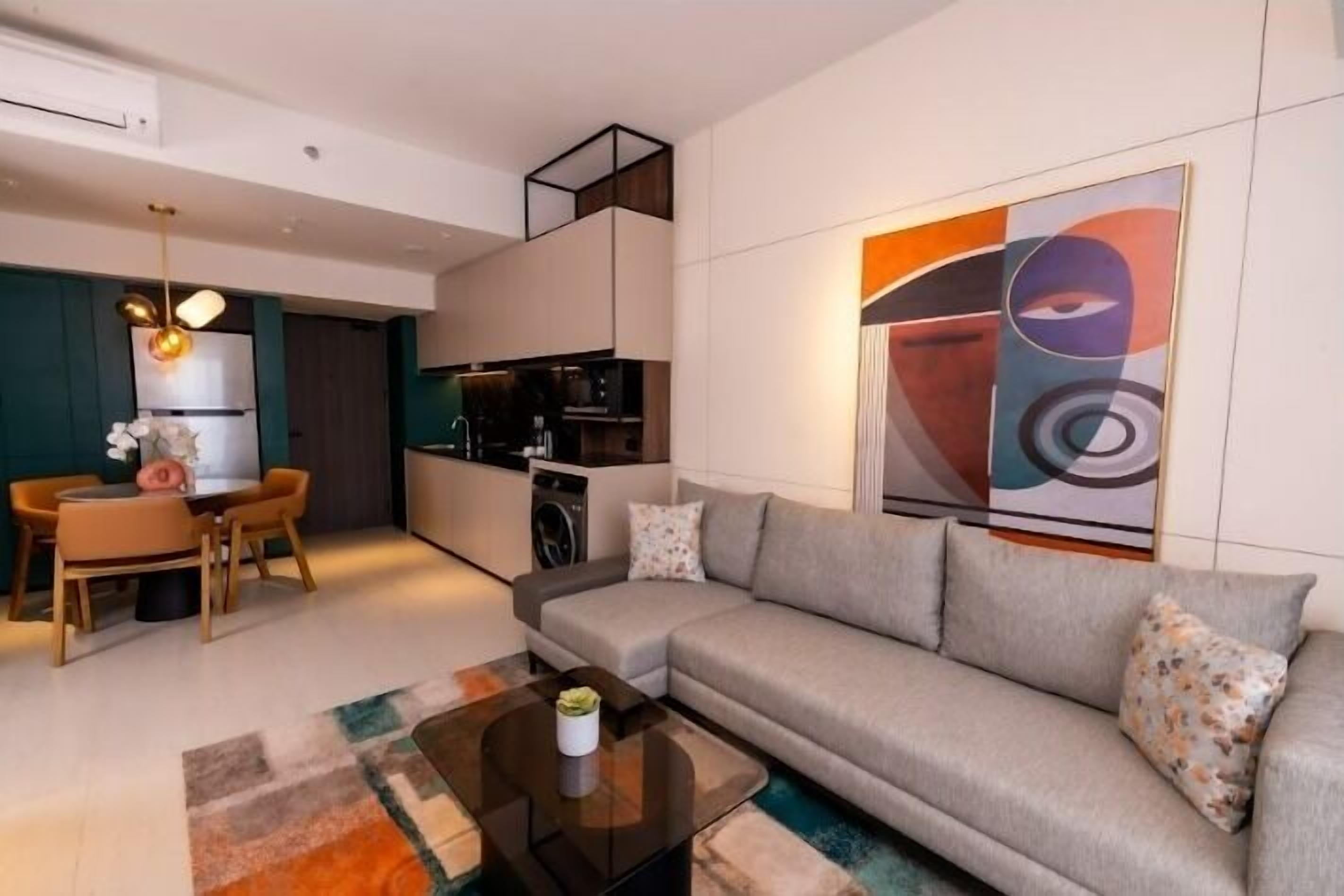 A modern living room with a sofa, coffee table, and a dining area with chairs and a table.