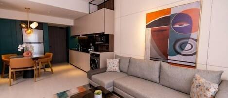 A modern living room with a sofa, coffee table, and a dining area with chairs and a table.