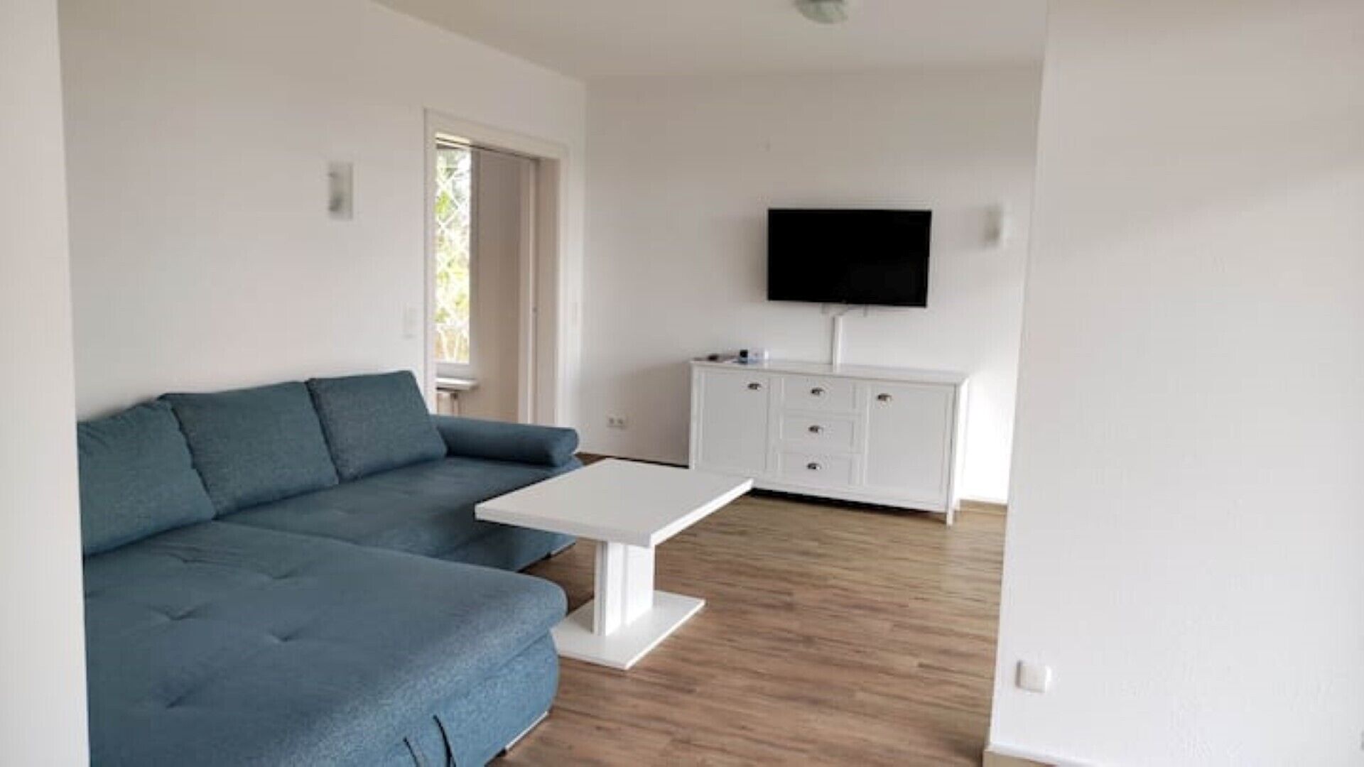 Un salon comprenant un canapé, une table basse, un téléviseur et un meuble.