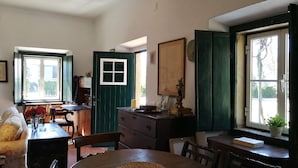 Uma sala de jantar acolhedora com uma mesa redonda, cadeiras, um armário de madeira e uma janela com vista para o exterior.
