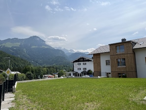 A building with a sign reading "Hotel Brunneck" in a mountainous area with a grassy foreground and a view of distant mountains.