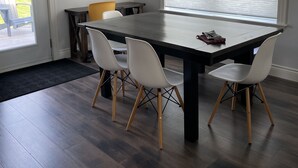 A dining area with a dark wooden table, white chairs, and a painting on the wall. - Countryside Getaway (Clyde River)