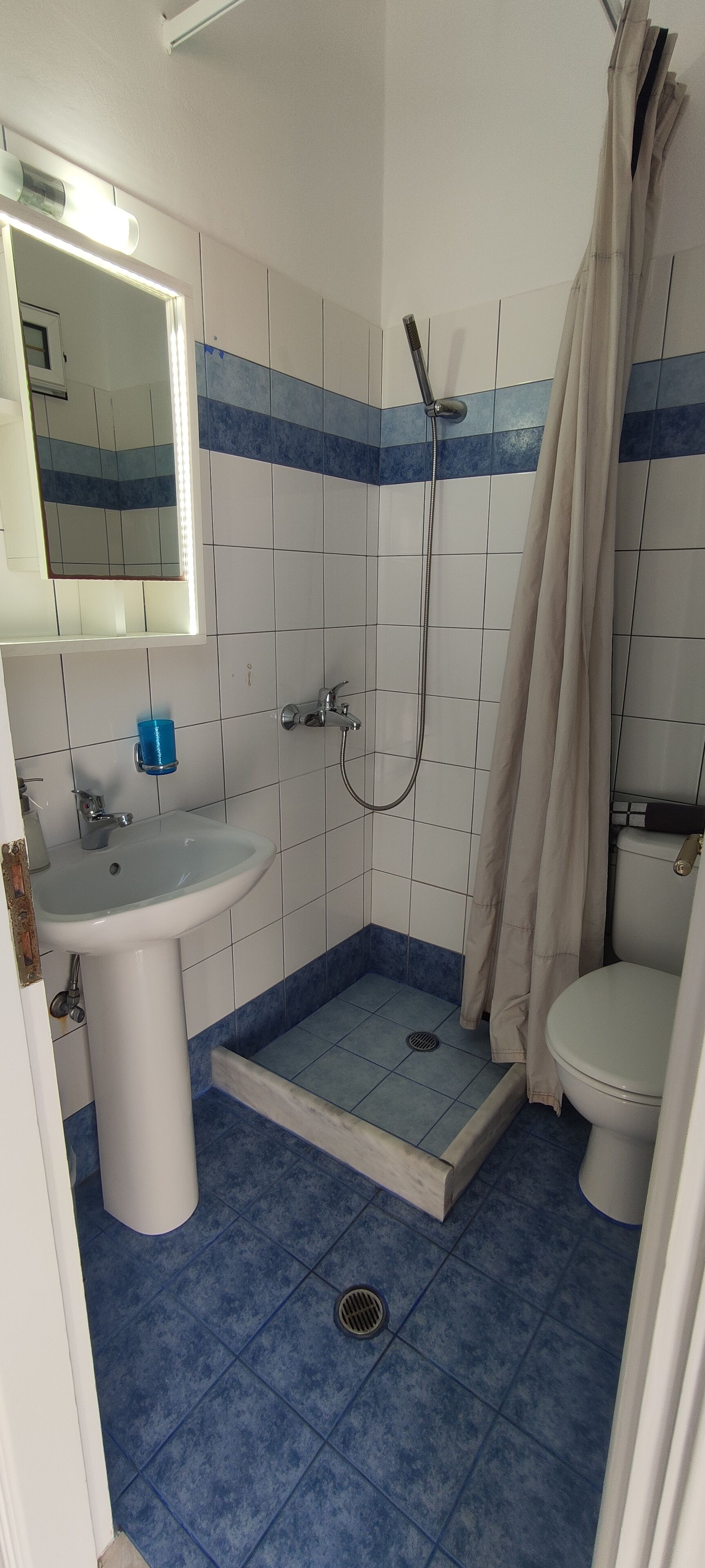 Een badkamer met een witte wastafel, een douche met een beige gordijn en een toilet.