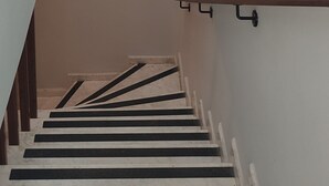 Una escalera con paredes blancas y un accesorio de iluminación en la parte superior.