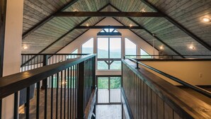 A wooden interior with a high ceiling and a view of the outdoors. - The Wanderlust Cabin (Ponca)