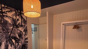 Un dormitorio con cama, armario, lámpara colgante y puerta que da a otra habitación.