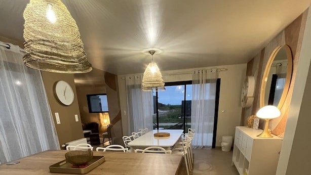 Una cocina moderna con una isla central, armarios blancos e iluminación colgante.