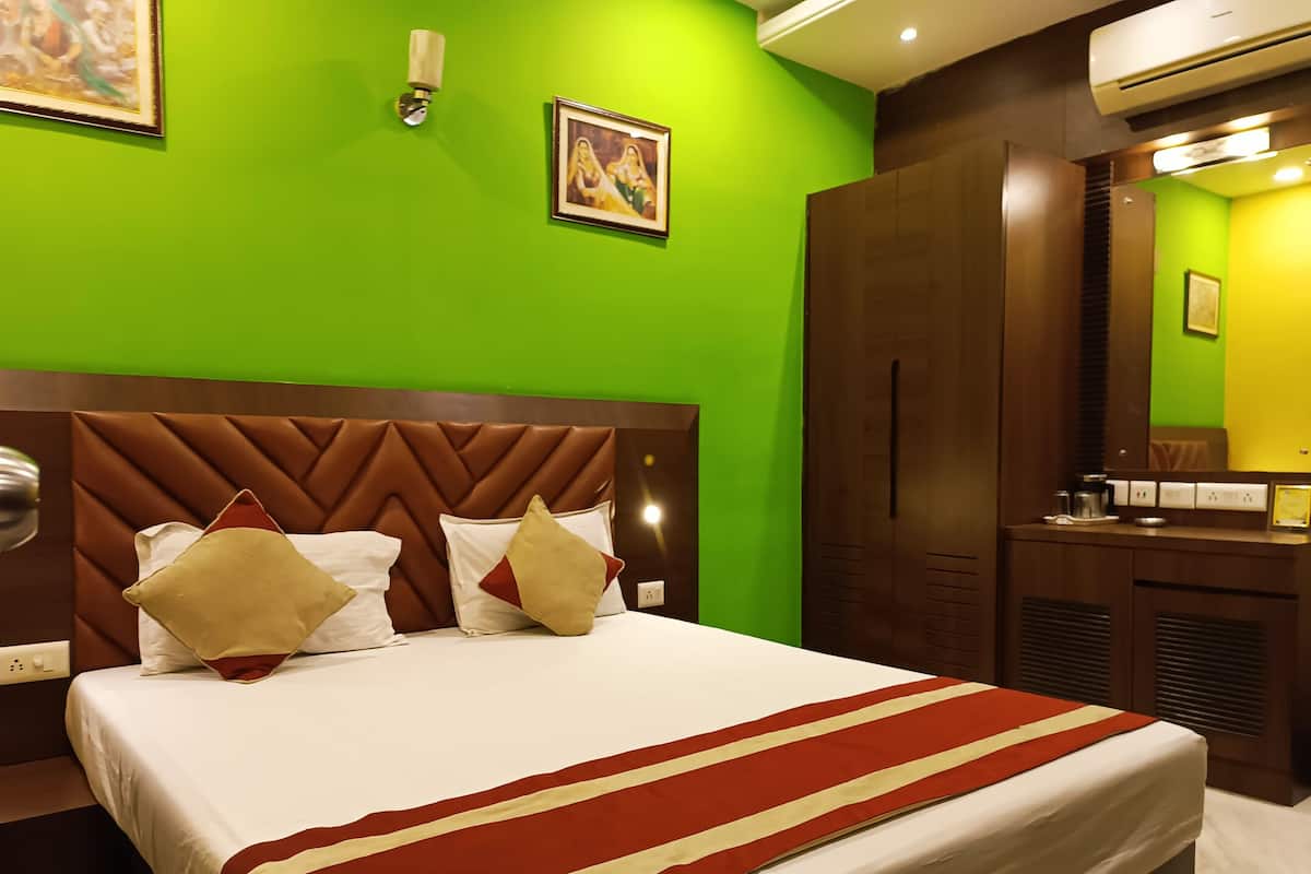 Ein Hotelzimmer mit einem Bett, grünen Wänden, einem Holzkopfstück und einem Spiegel.