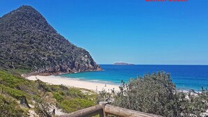 A coastal landscape with a beach, a mountain, and a clear blue sky. - Beach Haven, 3a Messines Street - 4 Minute walk to the beach, WiFi , Air Con (Shoal Bay)