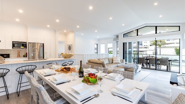 A modern kitchen with white cabinets, stainless steel appliances, and a dining area with a long table set for a meal.