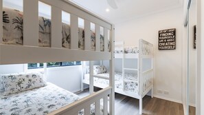 A child's bunk bed with floral bedding, a window with a view, and motivational wall art.