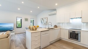 A modern kitchen with white cabinetry, a built-in dishwasher, and an oven. - Beach Haven, 3a Messines Street - 4 Minute walk to the beach, WiFi , Air Con (Shoal Bay)