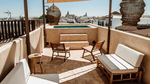 Una terraza en la azotea con piscina, zona de estar y vistas a la ciudad.