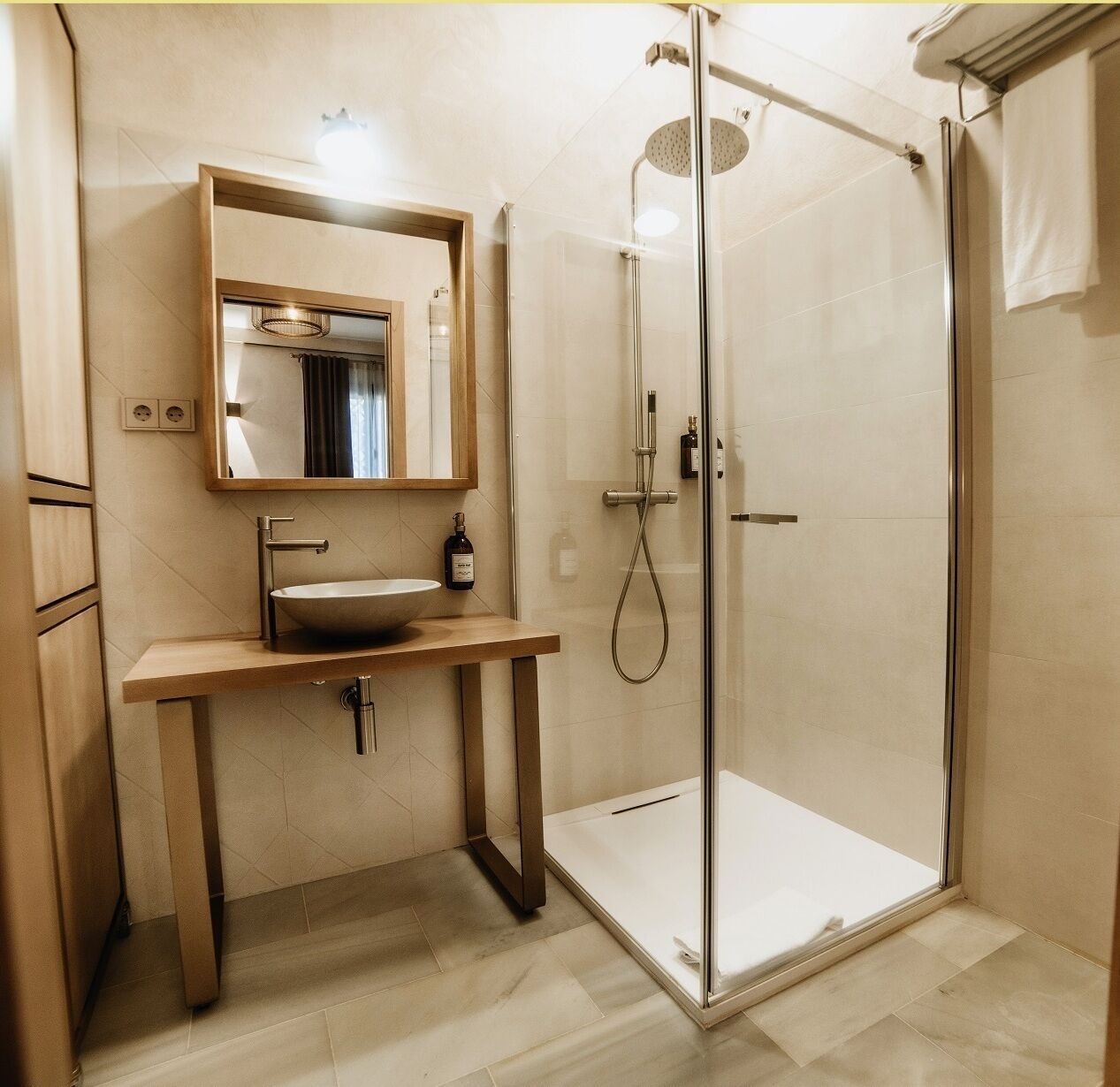 A modern bathroom with a glass-enclosed shower, a wooden vanity with a sink, and a mirror above it.