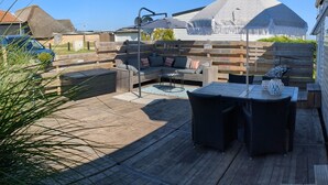 Een houten terras met buitenmeubilair, zoals een bank en een tafel.