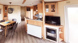 Een compacte keuken met een eethoek, een televisie en een ingebouwde open haard.