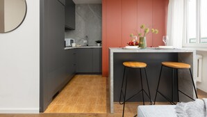 A modern kitchen with dark cabinets, a marble backsplash, and a central island with stools.