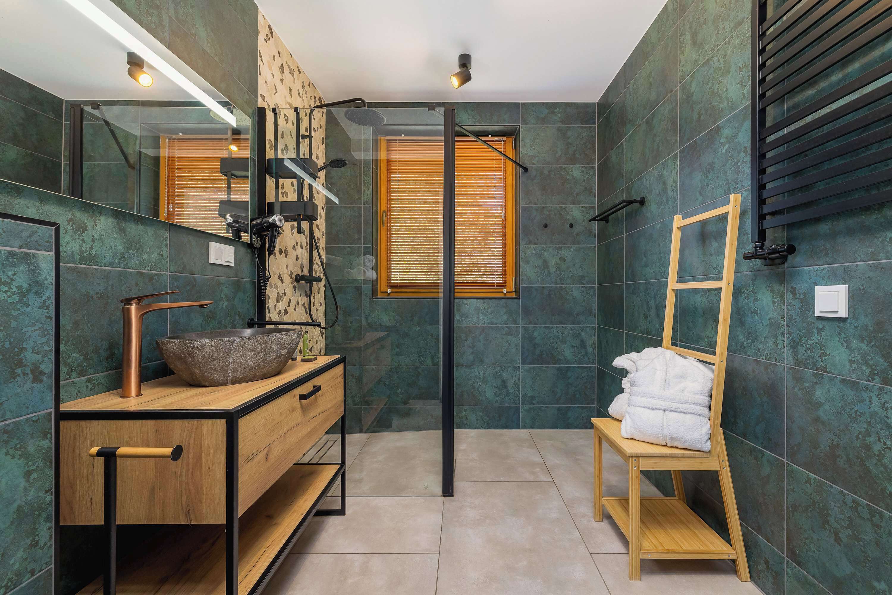 Une salle de bain moderne avec un meuble-lavabo en bois, un grand miroir, une cabine de douche en verre et un porte-serviettes.