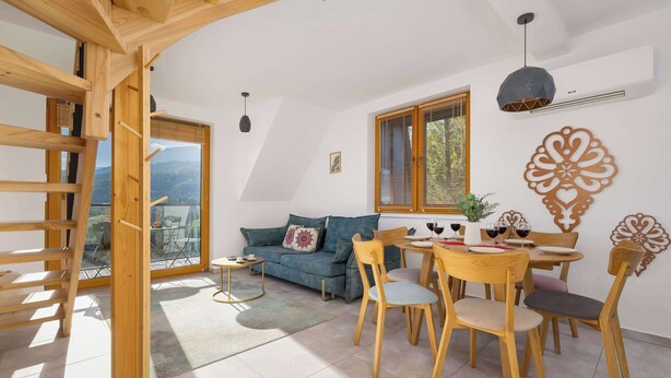 Ein modernes Wohnzimmer mit einer Couch, einem Esstisch, Stühlen und einer Holzleiter.