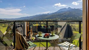 Ein Balkon mit Tisch und Stühlen mit Blick auf eine gebirgige Landschaft.
