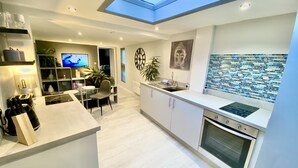 A modern kitchen with a skylight, a dining area with a TV, and a decorative wall. - A Hidden Gem With Private Hot Tub and Garden (Bournemouth)
