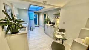 A modern kitchen with a glass dining table, a green chair, and a potted plant. - A Hidden Gem With Private Hot Tub and Garden (Bournemouth)