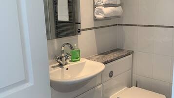 A modern bathroom with a white sink, a mirror, a toilet, and a towel rack.