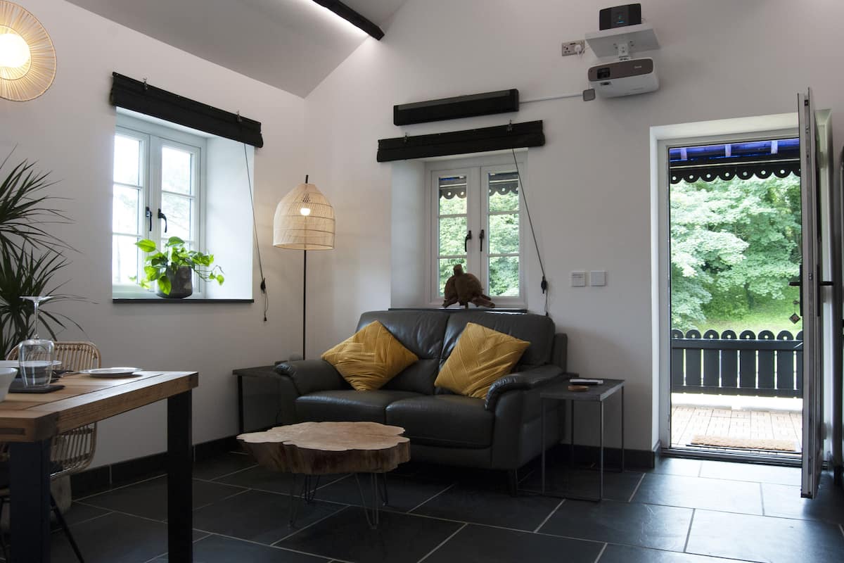 A modern living room with a grey sofa, two yellow cushions, a wooden coffee table, a floor lamp, and a potted plant.