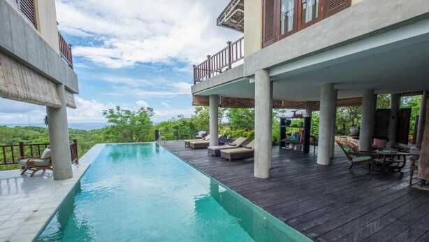 A swimming pool with a wooden deck and outdoor seating area. - Adila Bali (Ungasan)