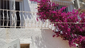 Um edifício branco com varanda, porta e janela.