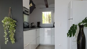 Uma cozinha moderna com armários brancos, bancada preta e uma janela.