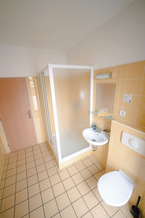 A bathroom with a shower, sink, and toilet. - Hotel Prácheň (Horazdovice)