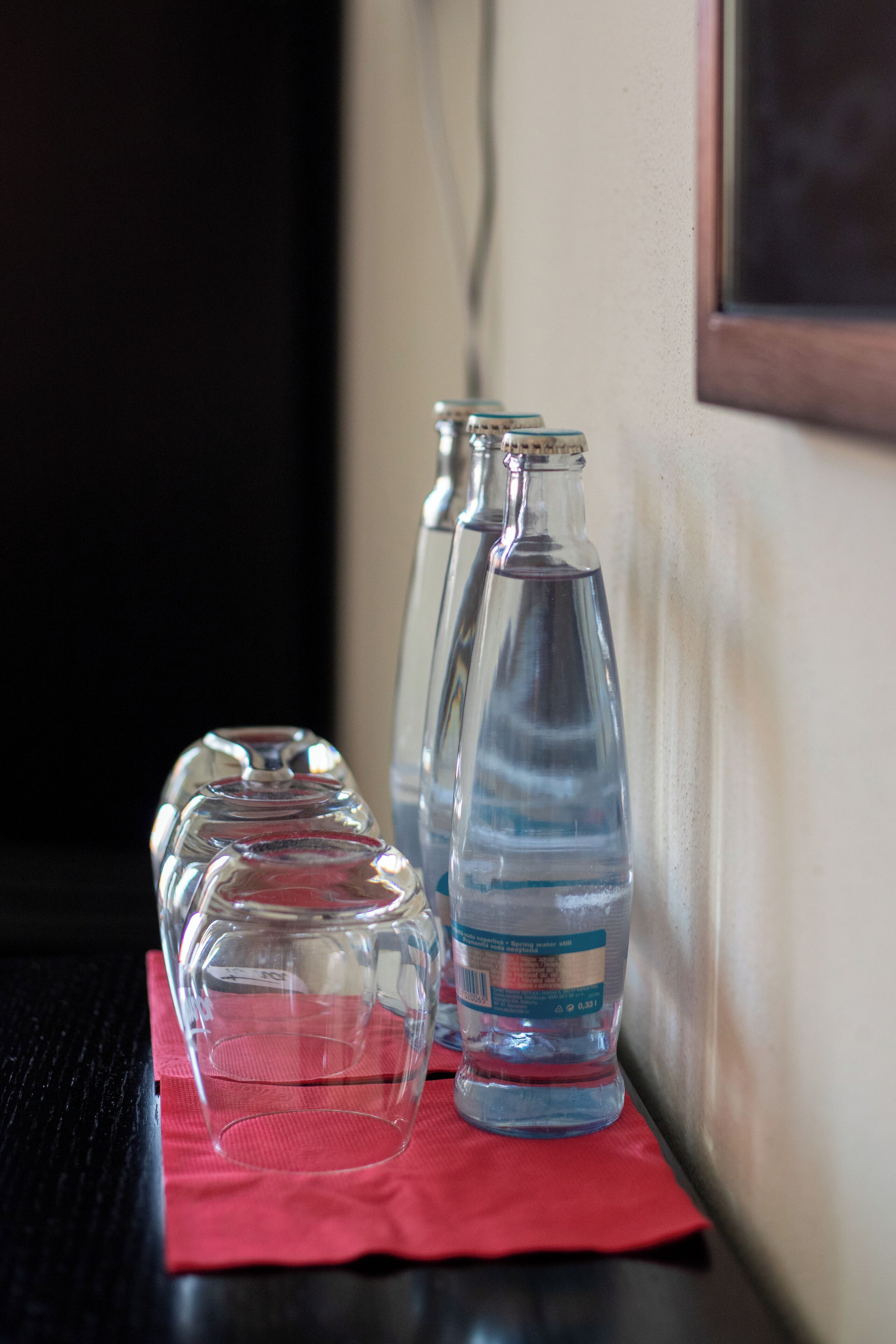 Cuatro botellas de agua de vidrio sobre un paño rojo.