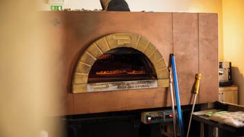 For ell de maó amb una pizza a dins, un esfregons i una eina de neteja.