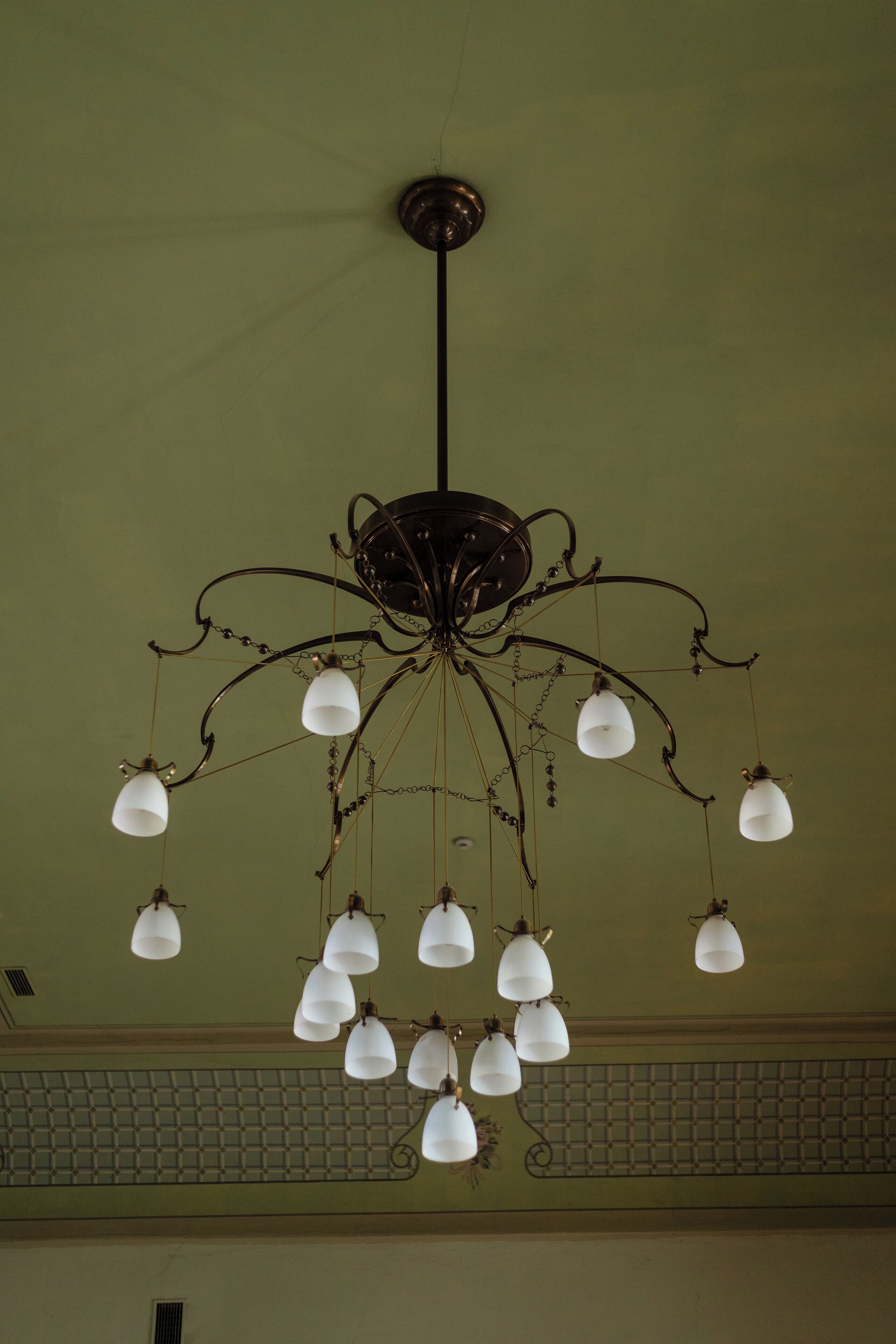 Un candelabro con varias lámparas blancas colgando de una estructura oscura central.
