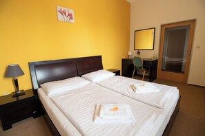 A hotel room with two beds, a desk, a chair, a lamp, and a mirror. - Hotel Prácheň (Horazdovice)
