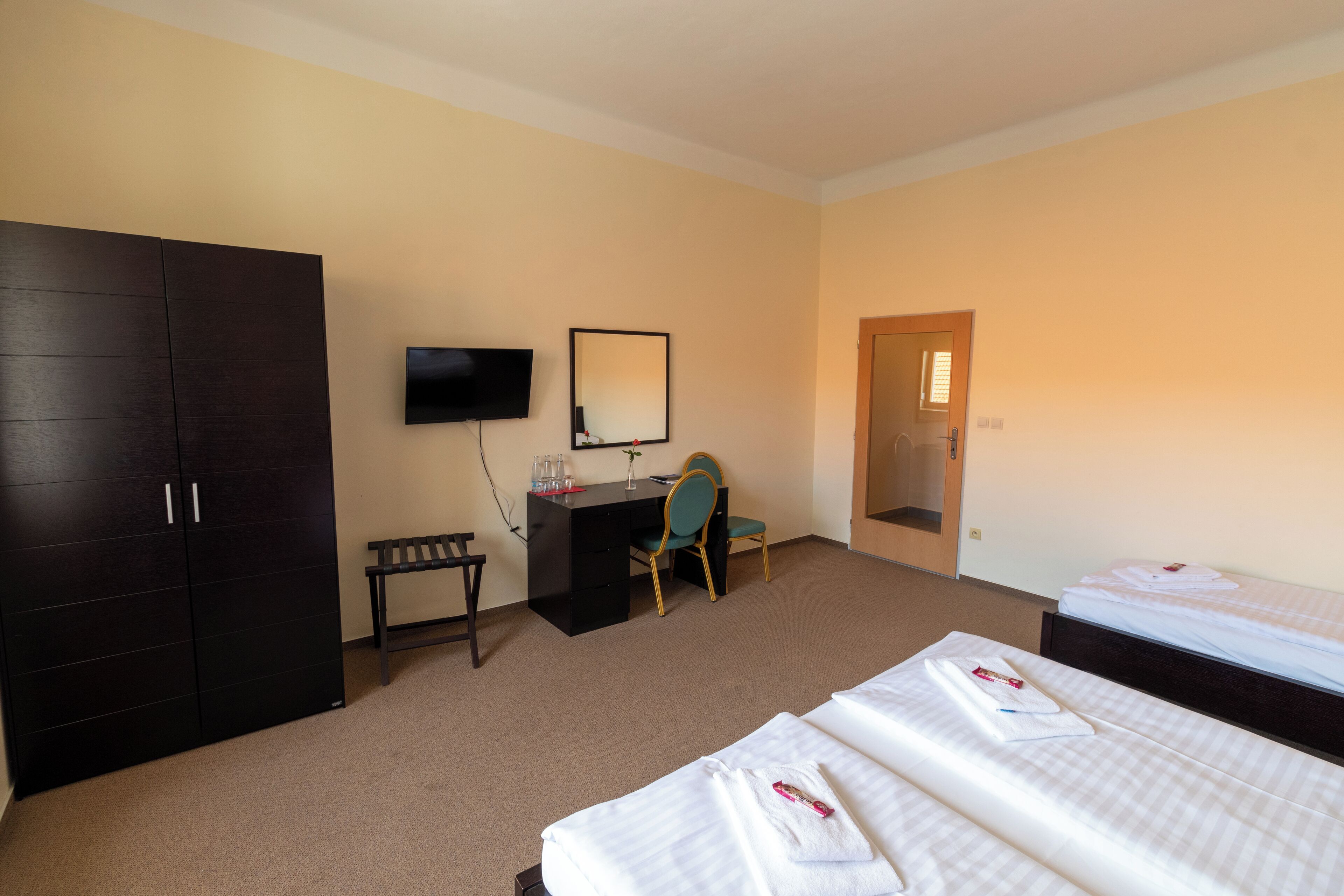 Habitación de hotel con un armario grande, un escritorio con silla, un televisor y dos camas.