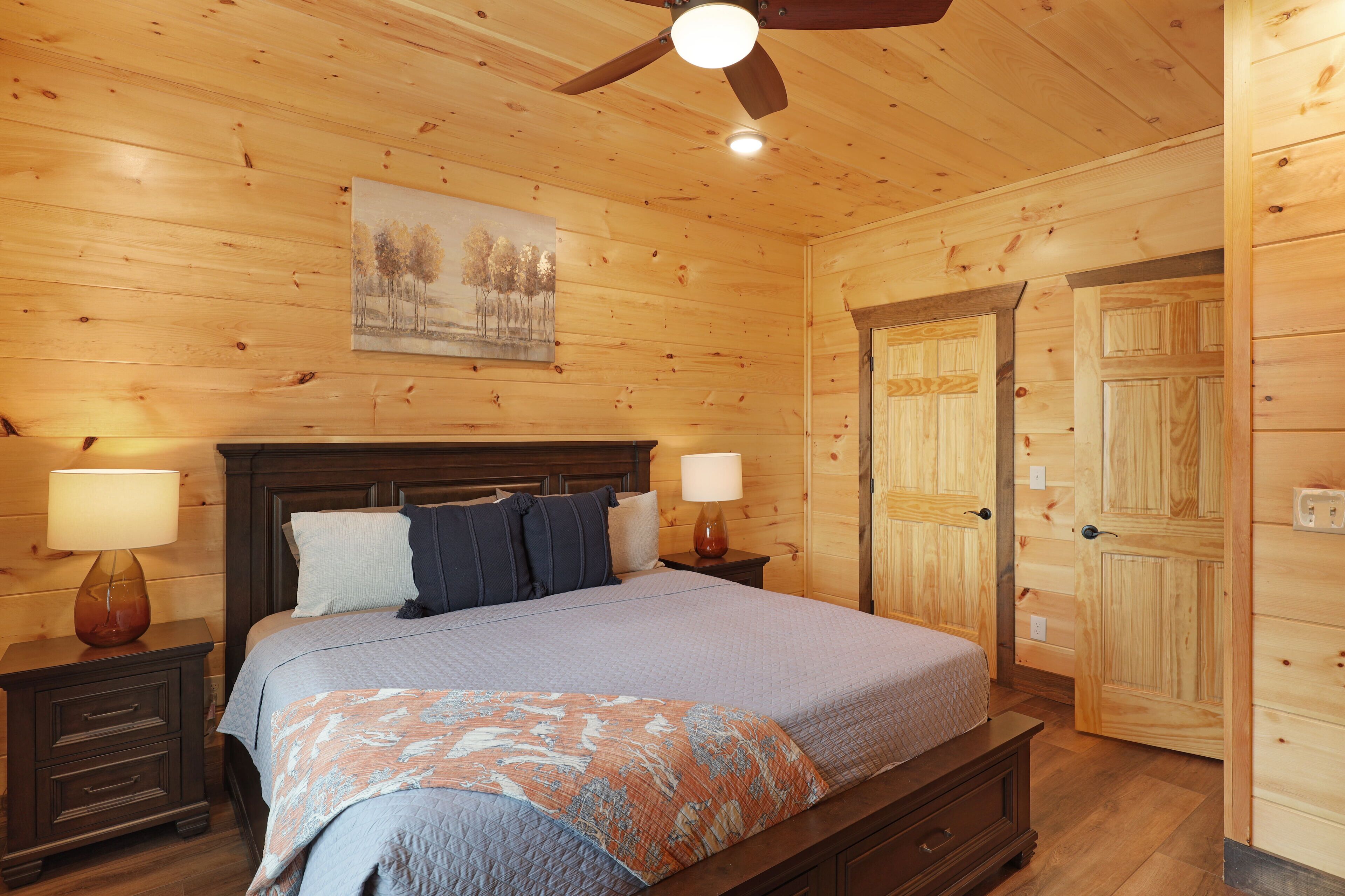 A wooden-paneled bedroom with a bed, nightstands, and a ceiling fan.