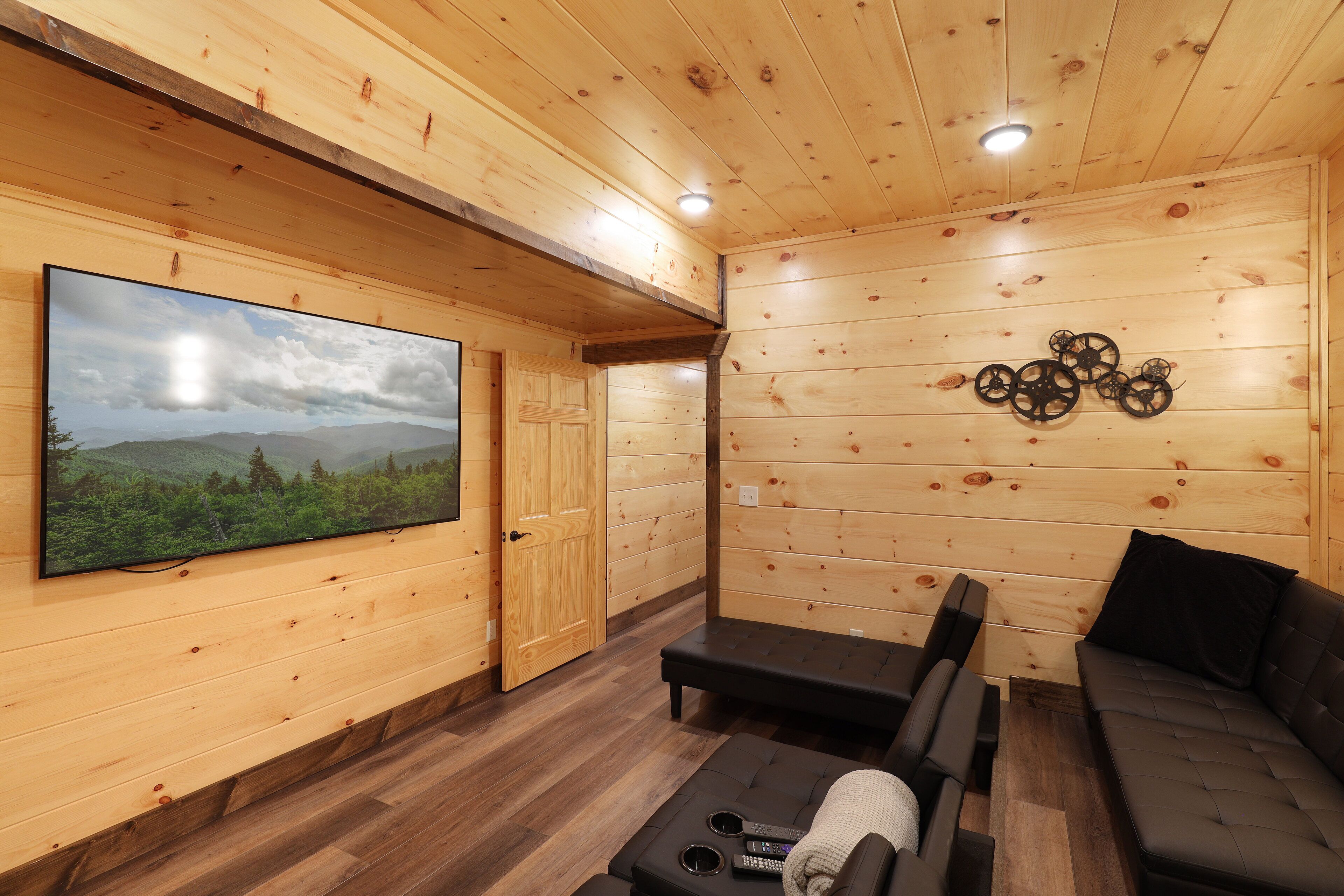 A wooden interior with a large TV, a sofa, and a massage table.