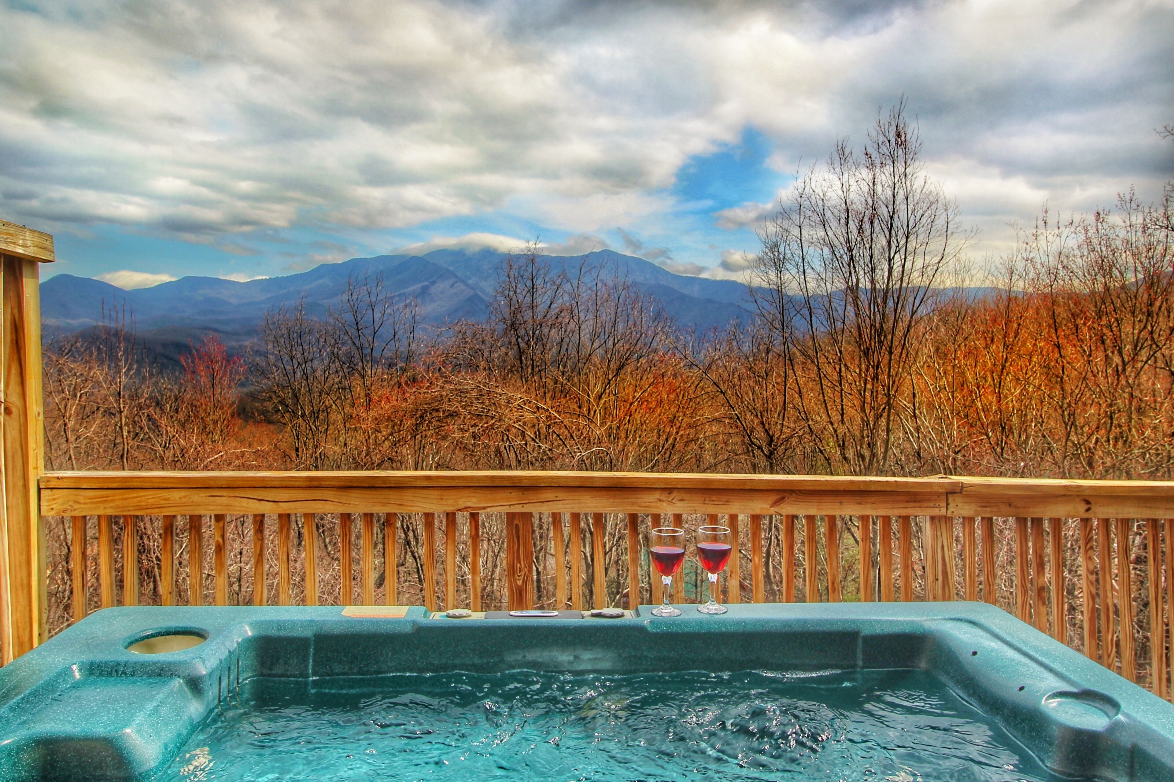 A hot tub with a wooden deck and a mountain view.
