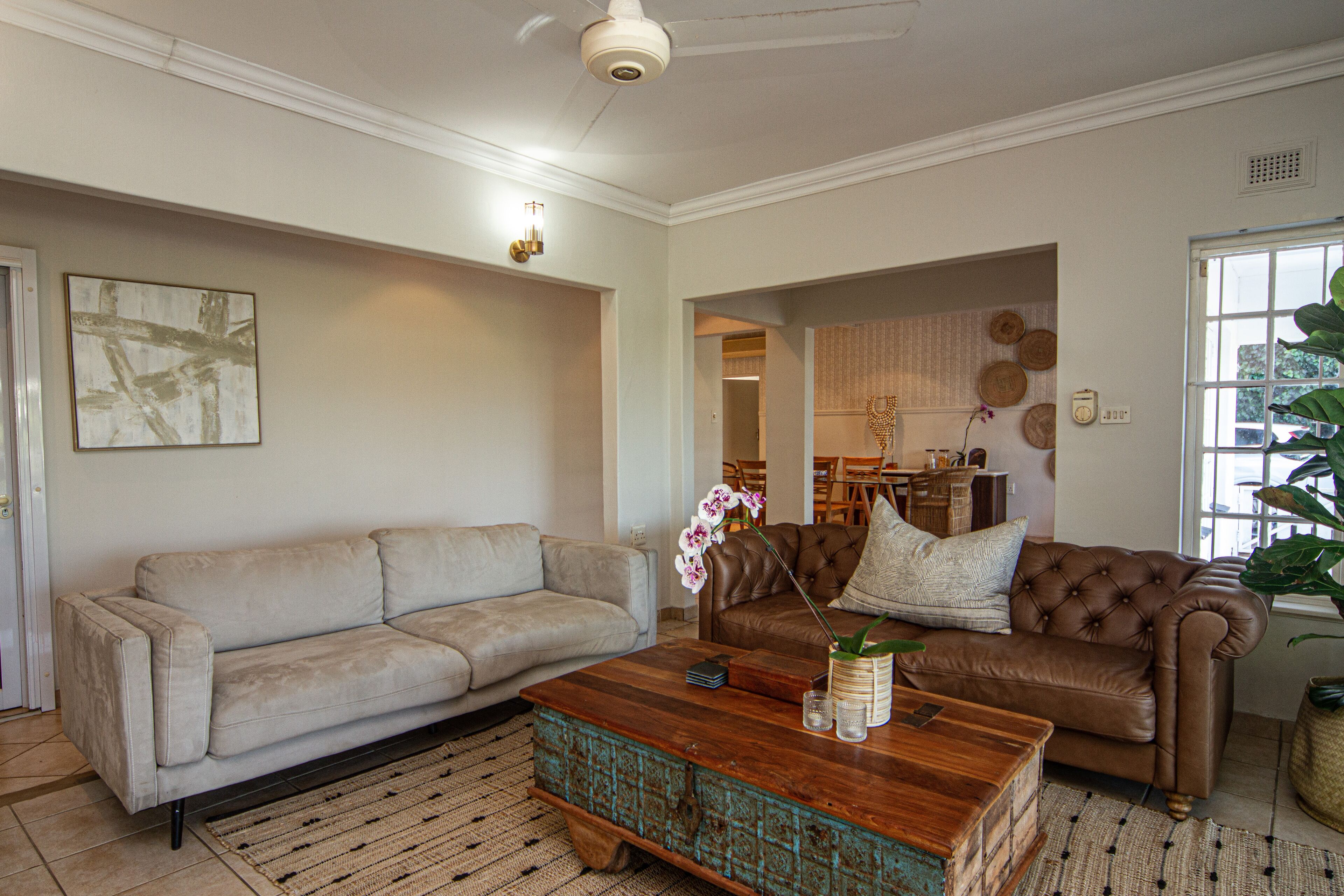 A living room with a beige sofa, a brown leather sofa, and a wooden coffee table.
