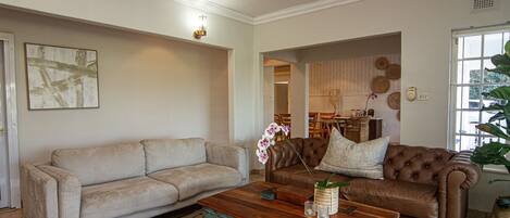 A living room with a beige sofa, a brown leather sofa, and a wooden coffee table.