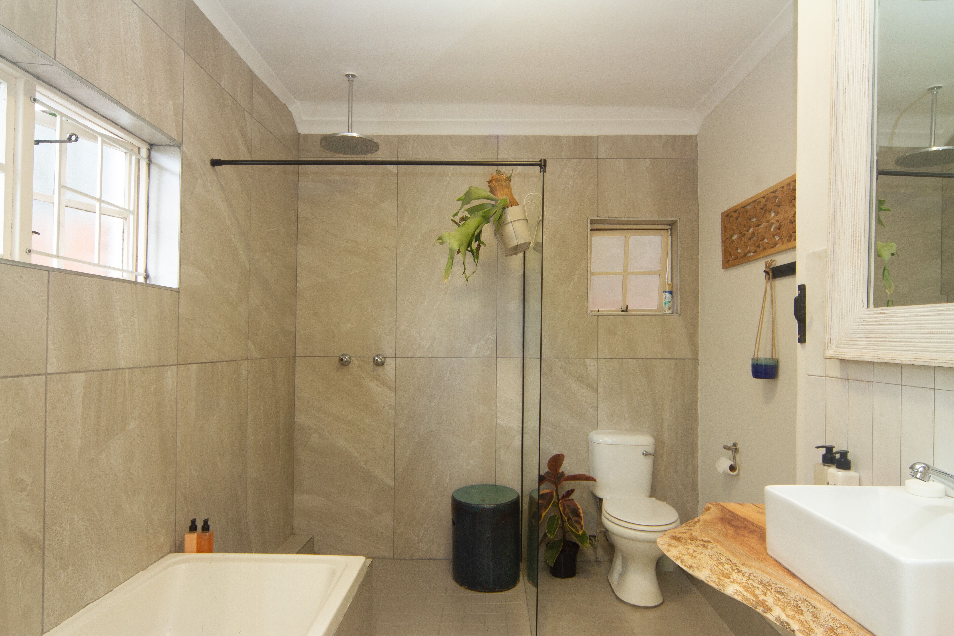 A modern bathroom with a glass-enclosed shower, a freestanding bathtub, and a wooden vanity.