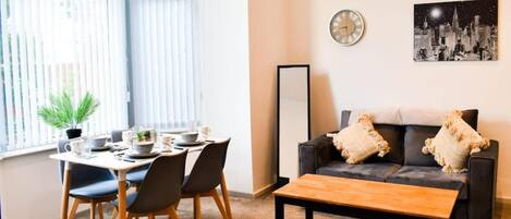 A modern living room with a dining area, featuring a sofa, coffee table, and a dining table set with chairs.