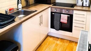 A compact kitchen with white cabinets, a microwave, a stove, and a toaster.