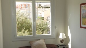 Een slaapkamer met een bed, een raam, een lamp en een plafondarmatuur.