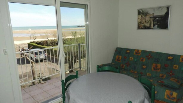 Een balkon met uitzicht op het strand, een groene bank en een tafel.