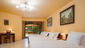 A hotel room with two beds, a desk, and a chair. There is a painting on the wall and a window with curtains. - La Hacienda  (Vilvoorde)